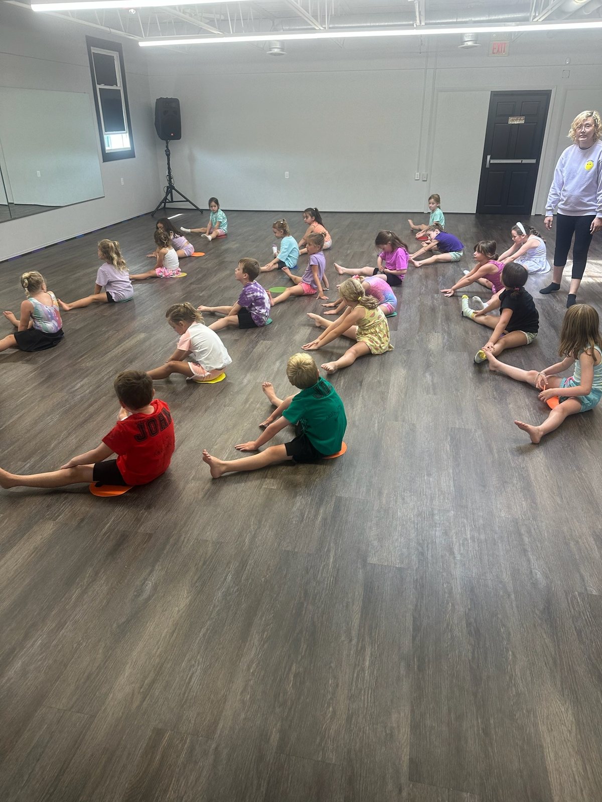 Children spread across the studio floor playing during a session, with an instructor at the side